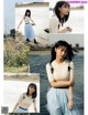 A woman in a white top and blue skirt posing by the water.