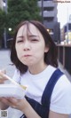 A woman eating a piece of food with chopsticks.