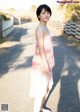 A woman in a pink and white dress standing on a road.