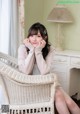 A woman sitting in a wicker chair with her hand on her chin.