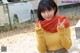 A woman in a yellow sweater and plaid skirt posing for a picture.