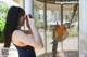 A woman taking a picture of a parrot in a cage.