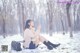 A woman sitting on the ground in the snow.