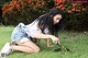 A woman kneeling on the grass with a rake.