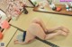 A naked woman laying on a tatami mat in a room.